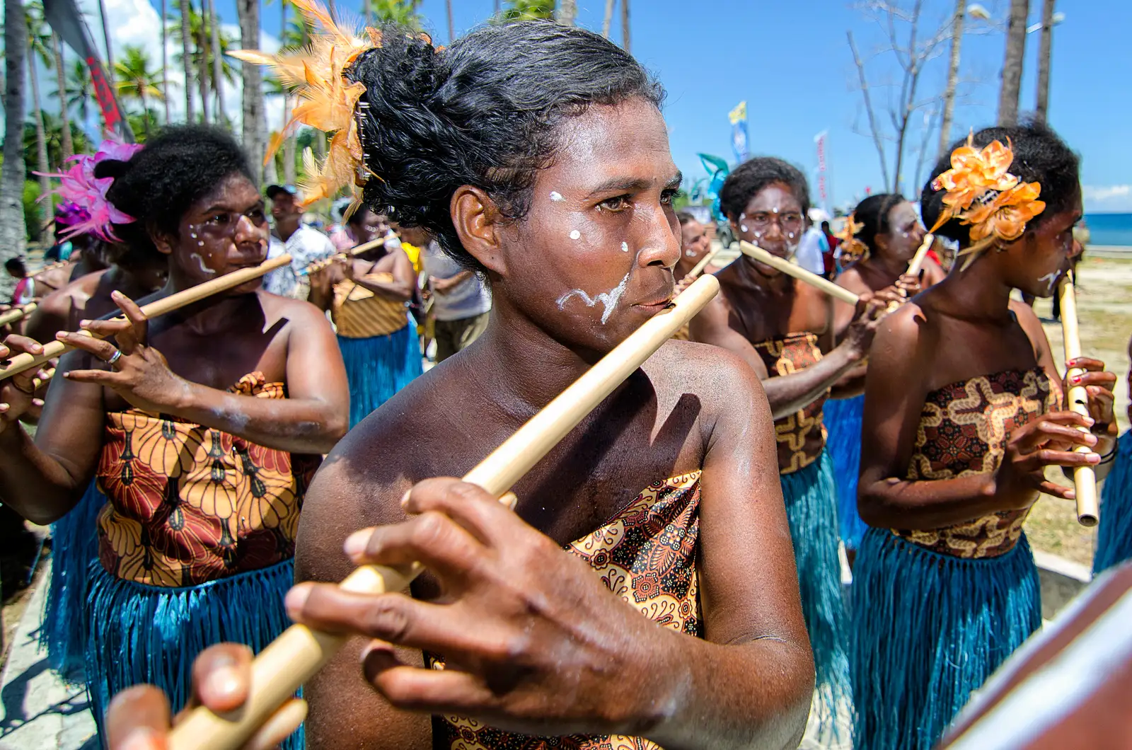 Papuan women playing bamboo suling flutes at a village gathering