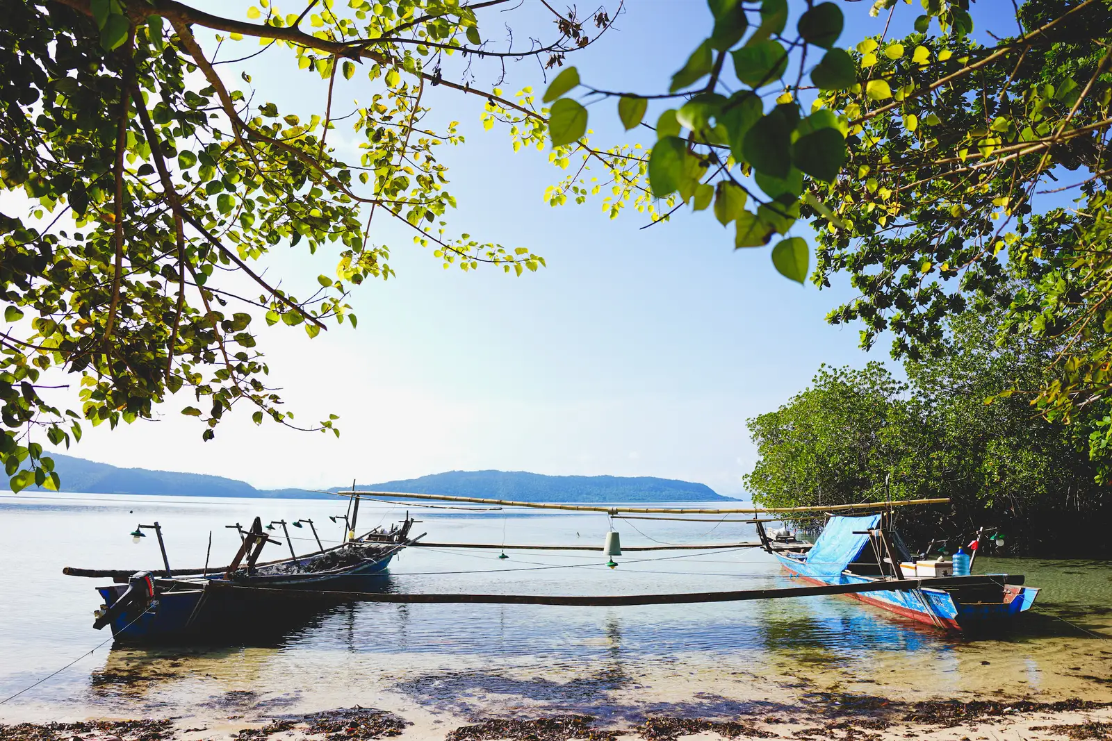 A locally built outrigger fishing boat moored off a village shore